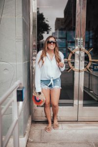 Ashley Zeal from Two Peas in a Prada pairs a tie front shirt and jean shorts for a nautical vibes outfit.